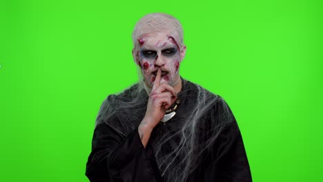 halloween zombie mann drückt den zeigefinger auf die lippen macht stille geste zeichen nicht erzählt geheimnis