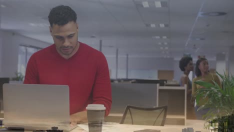 Animation-Des-Stadtbildes-über-Einem-Biracial-Geschäftsmann,-Der-Einen-Laptop-Im-Büro-Benutzt