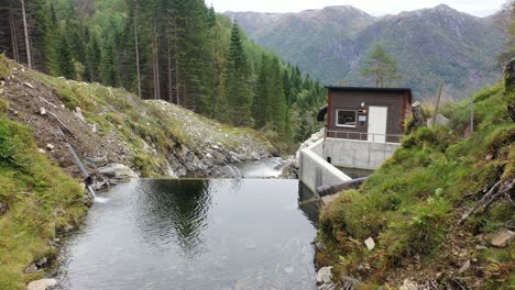 Antena-Estática-Sobre-La-Presa-De-Entrada-Del-Río-De-Montaña-A-La-Central-Hidroeléctrica-De-Markaani-En-Noruega---Mirando-Hacia-Una-Pequeña-Presa-Y-Una-Casa-Con-Válvulas-Y-Control-De-Flujo---Propiedad-De-Gestión-De-Activos-De-Captiva