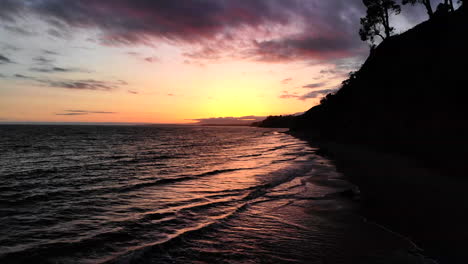 Luftdrohnenaufnahme-Eines-Orangefarbenen-Und-Violetten-Sonnenunterganghimmels-Und-Reflexionen-In-Den-Meereswellen-In-Santa-Barbara,-Kalifornien