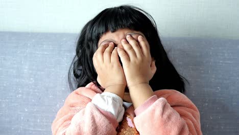 a young girl crying and covering her face with her hands