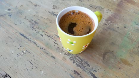 Slow-motion-of-cup-of-black-coffee-sitting-on-the-old-wooden-table