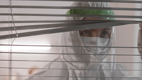 trabajador médico mirando a través de persianas horizontales
