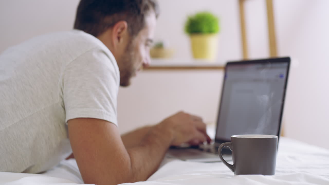 un joven usando una computadora portátil mientras toma café