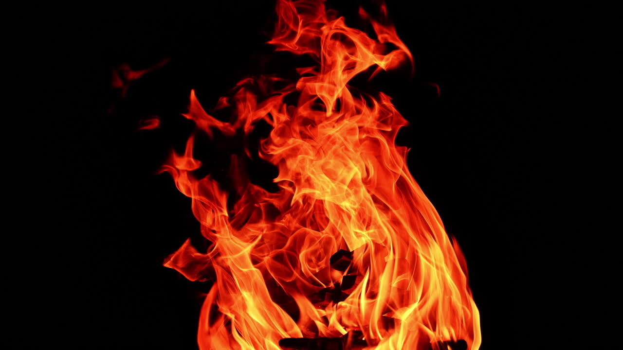 Wooden logs burning isolated at night. Tiny sparkles fly up into the air. Close up.