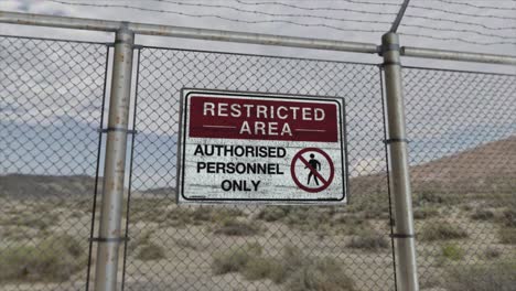 high quality 3d cgi render with a smooth dollying-out shot of a chainlink fence at a high security installation in a desert scene, with a restricted area - authorised personnel only sign