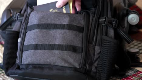 Man's-hand-seen-putting-his-passport-and-travel-documents-in-his-carry-on-luggage---isolated-close-up