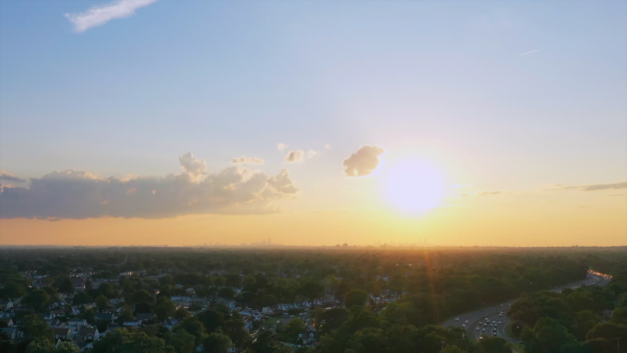 일몰 시간 경과 - 오른쪽에 교통량이 이동하는 고속도로가 있는 아름다운 일몰 동안 녹색 나무 꼭대기 위로 초고속 촬영