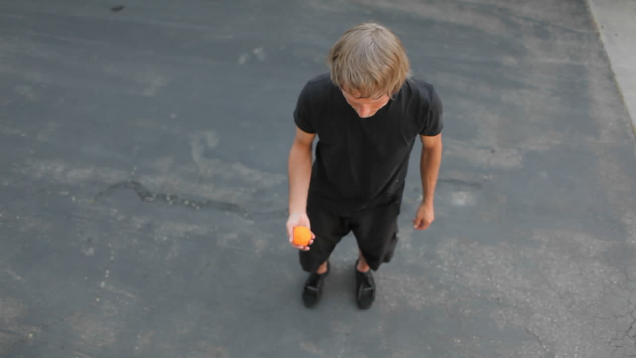 한 남자가 발로 공 하나를 머리 위로 앞뒤로 저글링합니다.