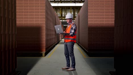Worker using laptop in a brick factory