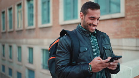 Young-man-texting-on-smartphone-and-smiling-outdoors.