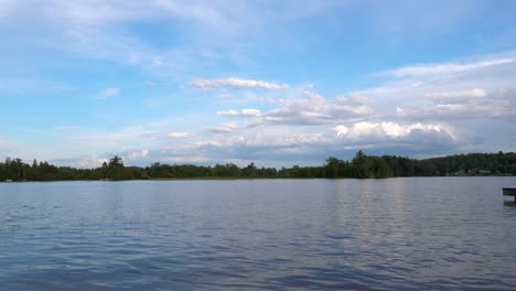 Magnificent-Lake-Scenery---Beautiful-Blue-Sky-with-Fluffy-Clouds-over-Tree-lined-Lake---Sunny-Summer-Day-60fps