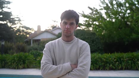 Young-Man-Standing-Near-Poolside-Outdoor-Looking-At-The-Camera