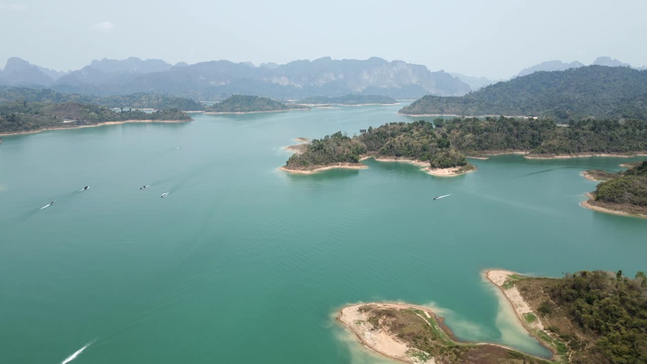 Stunning Aerial View of a Turquoise Lake with Numerous Islands and Boats, Surrounded by Lush Mountains