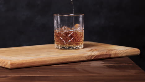 whiskey on the rocks, dark background wooden table