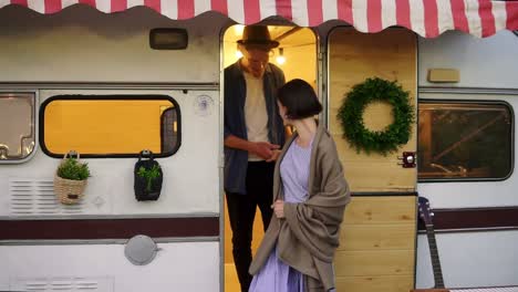 Portrait-Of-Romantic-Couple-Man-And-Woman-Coming-Out-From-The-Modern-House-On-Wheels-Outdoors