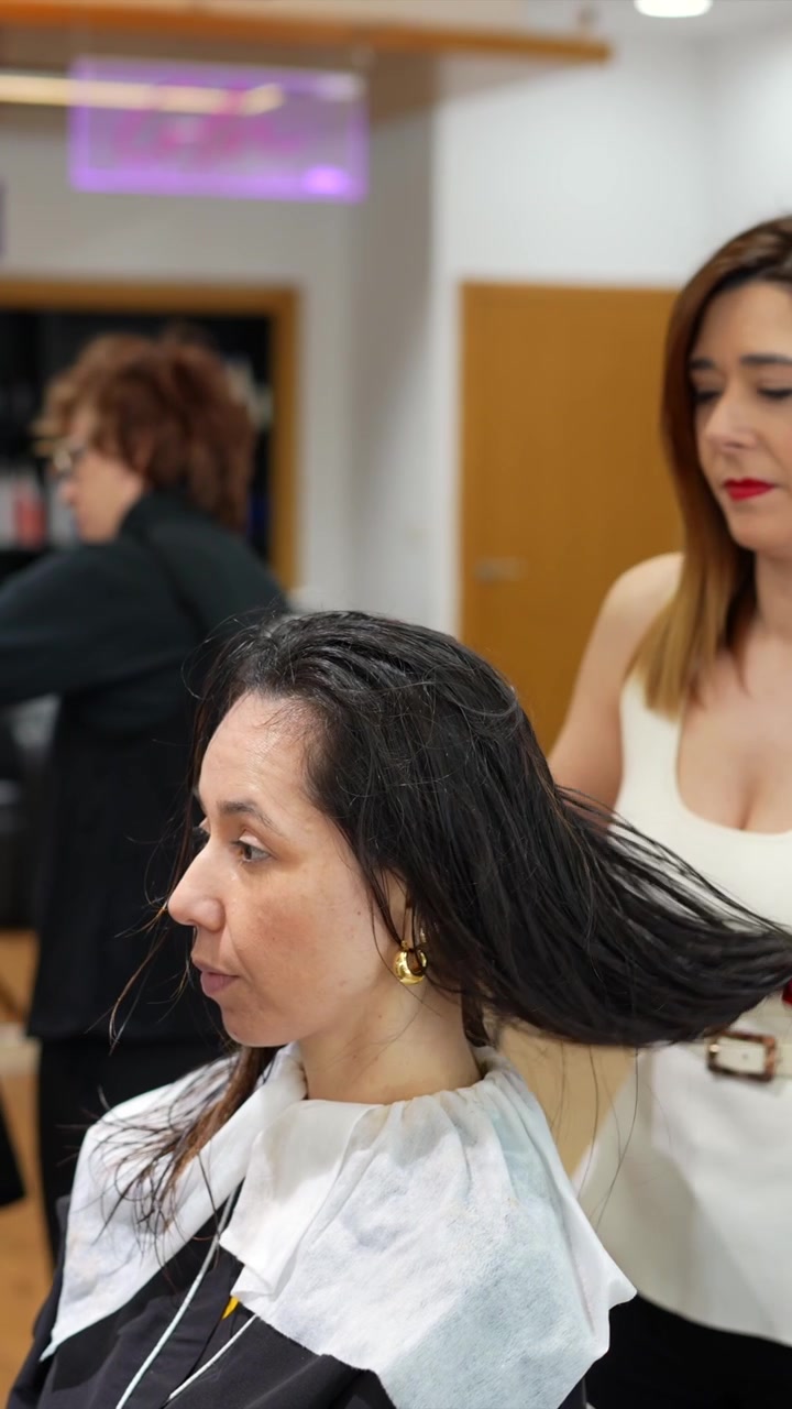 Peluquero profesional secando el cabello de un cliente en un salón.