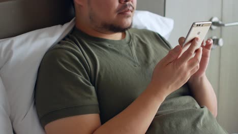 한 청년이 온라인 쇼핑을 위해 휴대폰을 사용하고 침실에 있는 침대에서 수다를 떨다