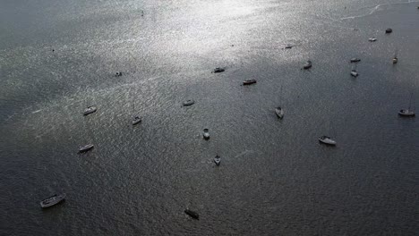 Aerial-drone-shot,-looking-down-on-the-Exe-Estuary-showing-beautiful-shimmering-water-and-moored-up-boats-in-Devon,-UK