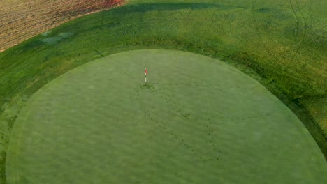 inclinação aérea para baixo acima da bandeira no fairway, pegadas na grama na geada do orvalho da manhã visível