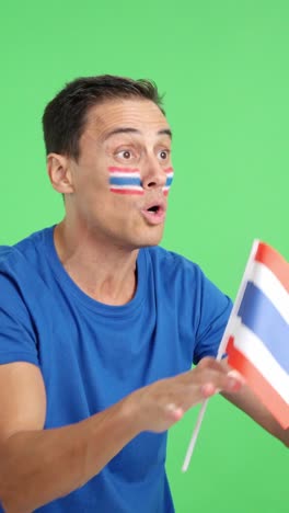 man cheering for thailand waving a national flag looking away
