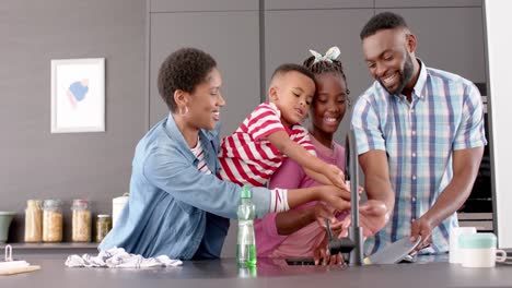 happy african american parents, son and daughter washing dishes and smiling in kitchen, slow motion