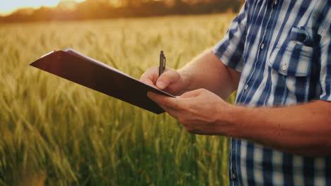 el agricultor firma el documento y le da la mano a un compañero en el fondo de un campo de trigo