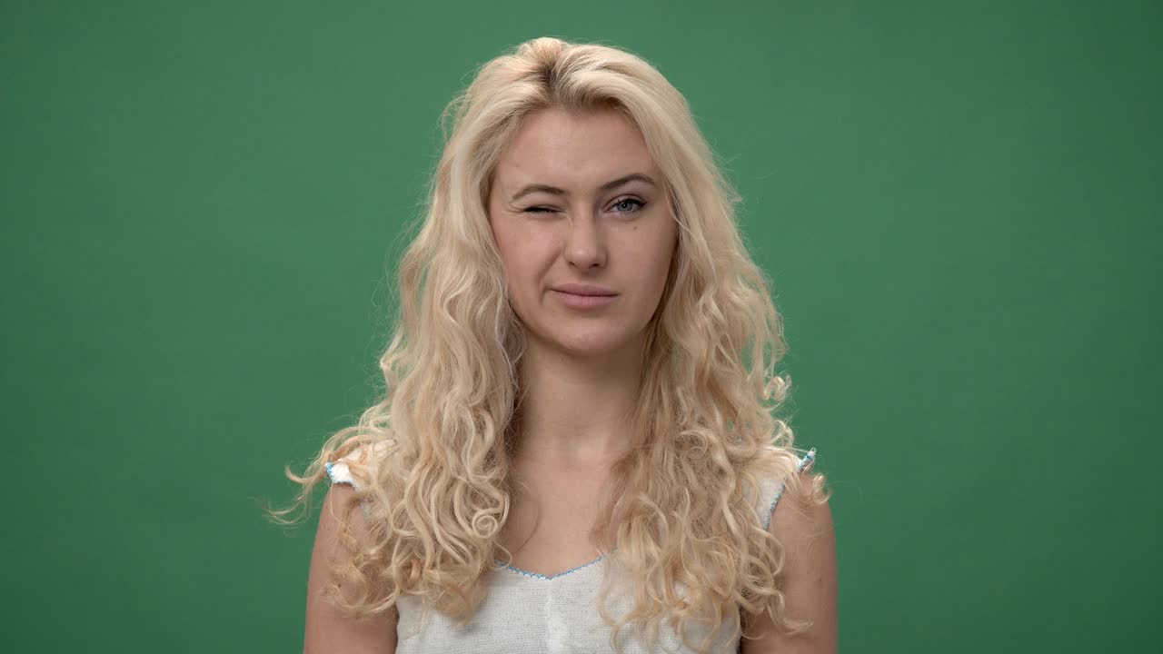 색 상자를 입은 젊은 금발 여성은 눈을 이고 미소 짓고, 크로마 키 녹색 화면 배경