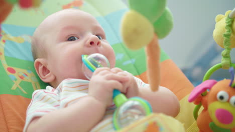 infant playing baby rattle. sweet baby face with toy. adorable kid with rattle