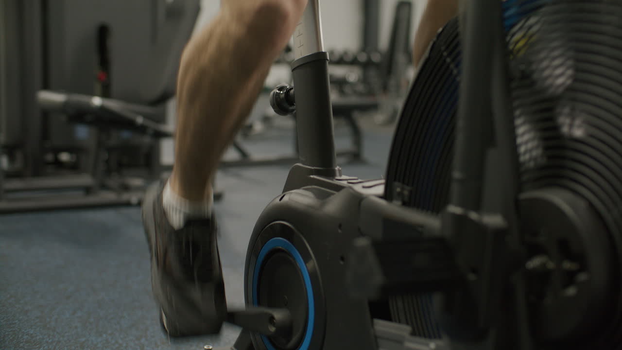 Athletic Man Doing Cardio Workout on Air Bike in Gym