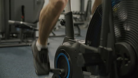 athletic man doing cardio workout on air bike in gym