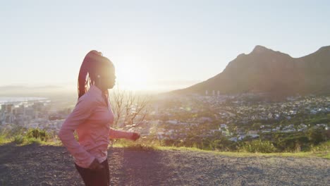 mujer afroamericana con auriculares haciendo ejercicio al aire libre corriendo en el campo durante el atardecer