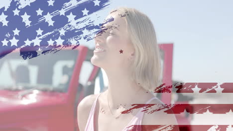 animation of flag of usa over happy caucasian woman by car on beach