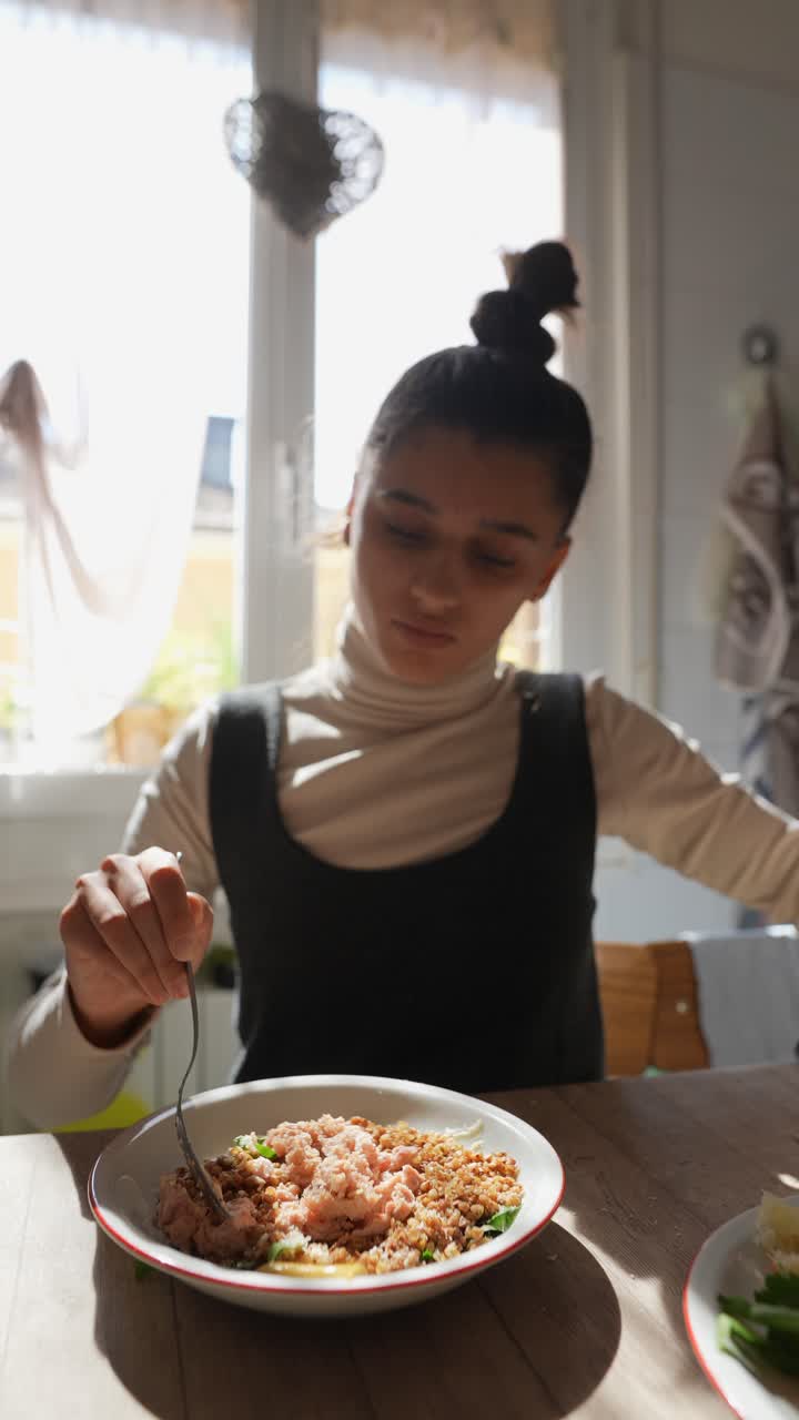 una mujer joven comiendo en casa.