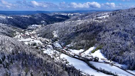 drone slow fly in the meurthe valley, habeaurupt, in plainfaing with snow covered landscape during springtime with blue sky and big clouds