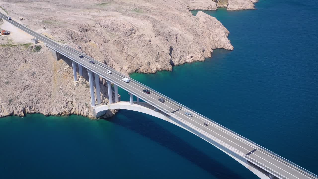 Aerial tracking shot over traffic driving across Pag Bridge in Croatia