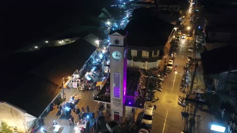 aerial footage of the vietnamese memorial clock tower in nakhon phanom province, thailand surrouned by lively night walking street