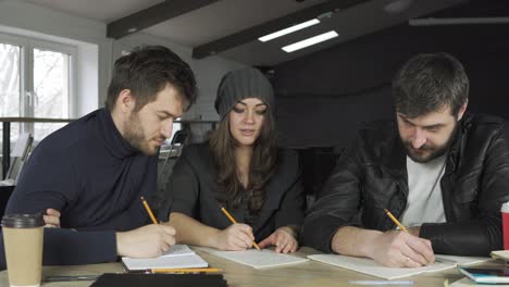 team of young professionals having a meeting in a creative office. taking notes and brainstorming. business discussion. coffee cups on the table. shot in 4k