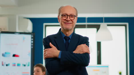 elderly businessman looking at camera crossing arms and smiling