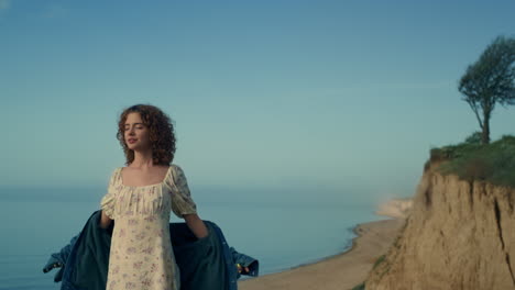 mujer pacífica de pie en la playa sola con los ojos vestidos. chica extendiendo las manos.