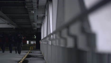 camera moving towards swat team with automatic rifles on construction bridge