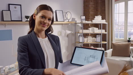 female architect reviewing blueprints and digital plans in her office