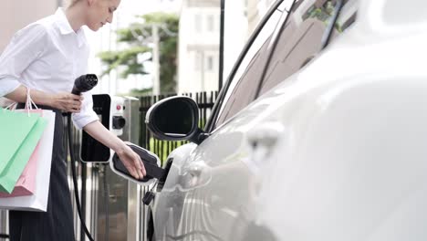 progressive businesswoman unplug charger plug from charging station to his ev.