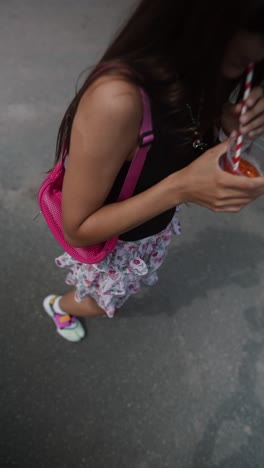 woman holding a drink on the street