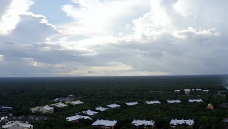 Beautiful-aerial-drone-shot-of-the-tropical-coastline-of-playa-del-carmen-with-large-vacation-resorts-and-a-large-bird-flying-with-the-drone-in-Riviera-Maya,-Mexico-on-a-warm-sunny-summer-day