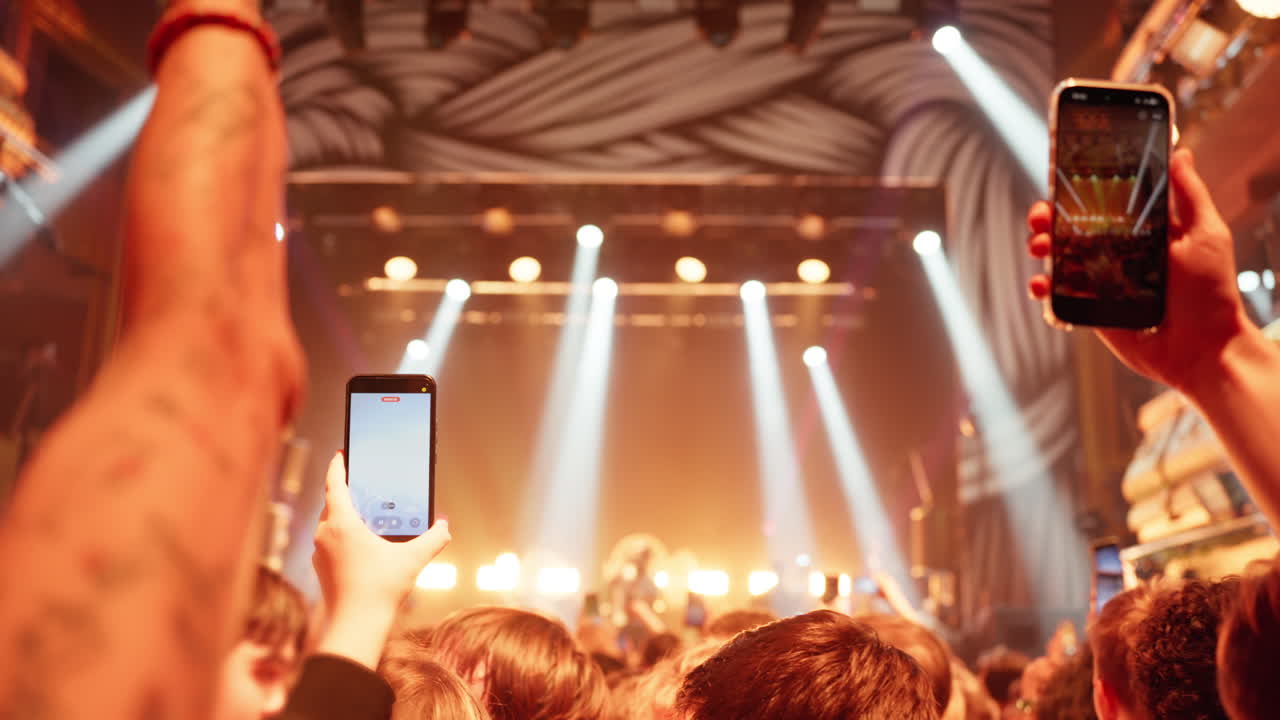 Multidão em Concerto Gravando Performance ao Vivo com Smartphones e Luzes Brilhantes do Palco