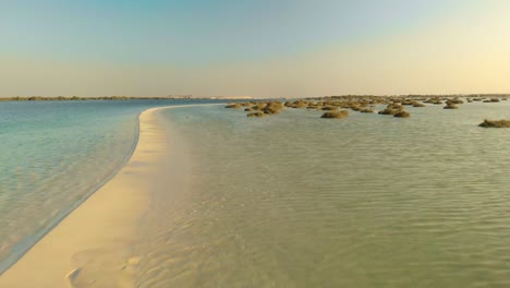 sand bank splitting ocean from shallow sea waters with mangrove low drone aerial