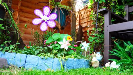 molino de viento de mariposa infantil giratorio colorido que sopla en la brisa entre una variedad de flores y plantas florecientes tiro de ángulo bajo