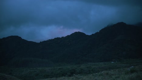 Nubes-Oscuras-Sobre-Las-Montañas-Con-Colores-De-Puesta-De-Sol-En-La-Distancia