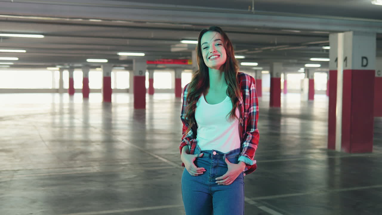 alegre joven caucásica sonriendo y mirando la cámara en un estacionamiento vacío